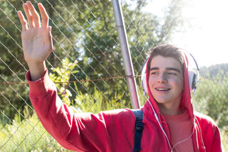 young man or student with mobile phone and headphones outdoors