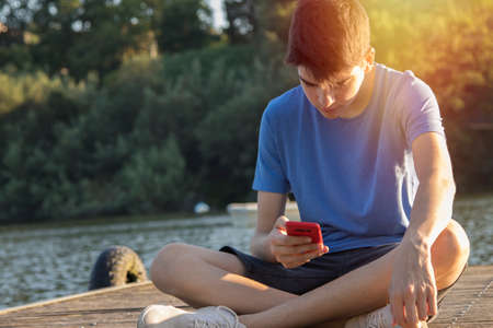 young man with mobile phone at sunset outdoorsの写真素材
