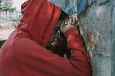 portrait of young man with hood leaning on the wallの写真素材