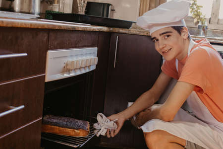 young boy removing cake or cake from the ovenの写真素材