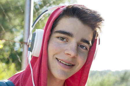 young man or student with mobile phone and headphones outdoors