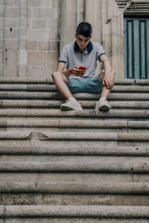 young teenage man with mobile phone in the city outdoorsの写真素材