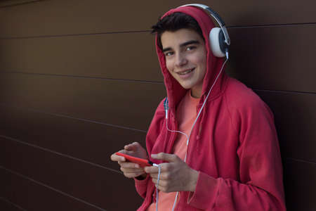 young man or student with mobile phone and headphones outdoors