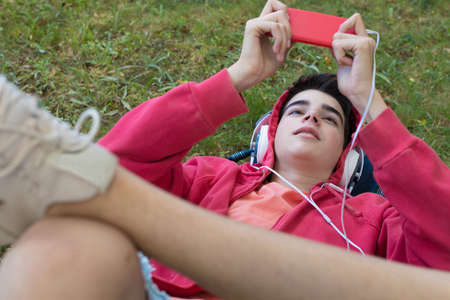 top view portrait of young man with mobile phone and headphones lying in the fieldの写真素材