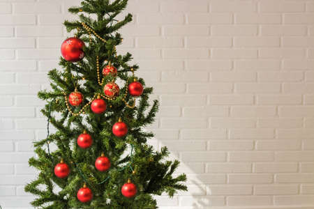 christmas tree with ornaments on white brick wall backgroundの写真素材