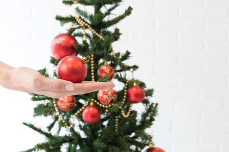 hand with christmas ball and tree with ornamentsの写真素材