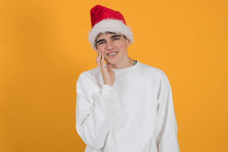 young teenage man with santa claus hat isolated on color backgroundの写真素材