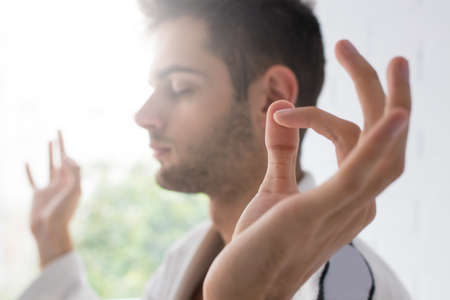 man hand in foreground with yoga concentration and meditation gestureの写真素材