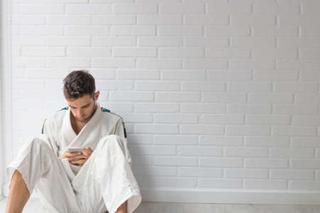 young man with phone in martial arts gymの写真素材