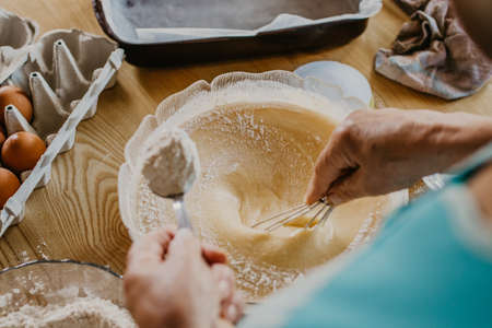 adult woman in the kitchen kneading the mix for sweets and dessertsの写真素材
