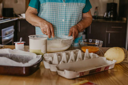 adult woman in the kitchen kneading the mix for sweets and dessertsの写真素材
