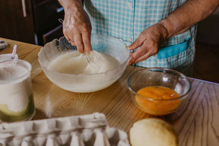 adult woman in the kitchen kneading the mix for sweets and dessertsの写真素材