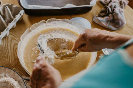 adult woman in the kitchen kneading the mix for sweets and dessertsの写真素材