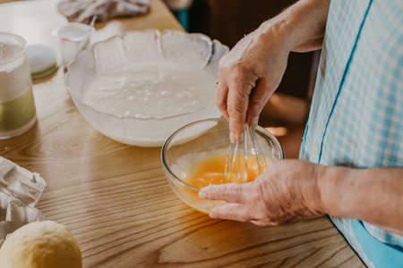 cook mixing and whisking eggs and ingredients for sweets and pastriesの写真素材