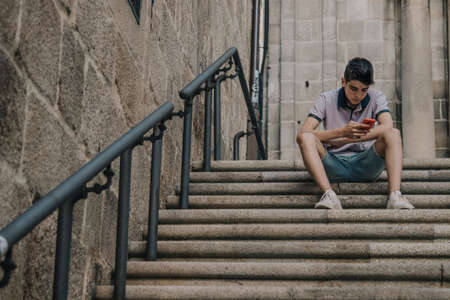 young teenage man with mobile phone in the city outdoorsの写真素材