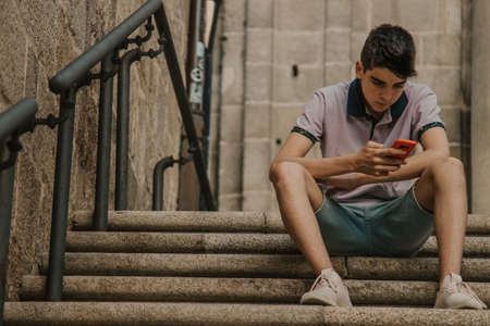 young teenage man with mobile phone in the city outdoorsの写真素材
