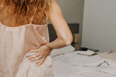 adult woman in the bedroom with symptoms of muscle painの写真素材