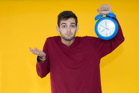 young man with alarm clock over color background