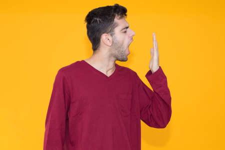 young man yawning with sleep isolated on color backgroundの写真素材