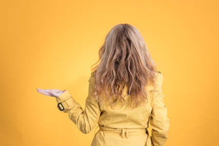 woman from behind with raincoat isolated on color background