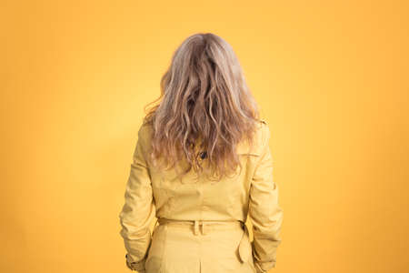 woman from behind with raincoat isolated on color background