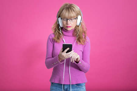 woman with headphones and mobile phone on color backgroundの写真素材