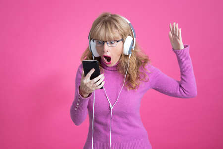 adult woman with mobile phone and expression of amazement or surprise on colored background