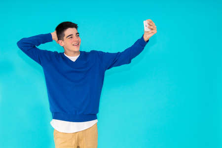 young teenage man with mobile phone isolated on color backgroundの写真素材