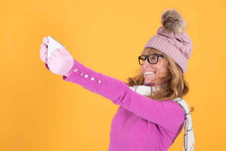 woman in winter with mobile phone on color background