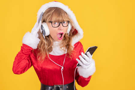 santa claus with mobile phone and headphones with surprise expression