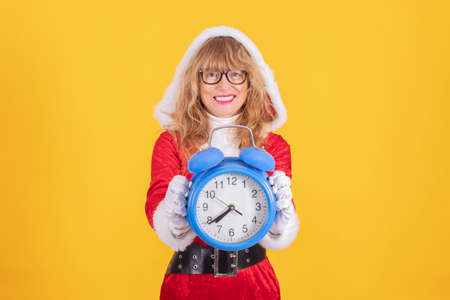 santa claus woman at christmas with clock or alarm isolated on color background smilingの写真素材
