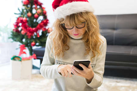 adult woman with christmas hat and mobile phone at home