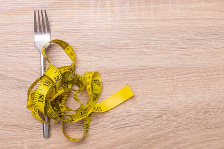 fork with tape measure, diet and weight loss conceptの写真素材