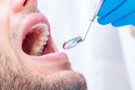 dentist with tools working on the patient's mouth