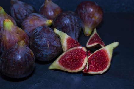 natural black figs grouped and open on black backgroundの写真素材