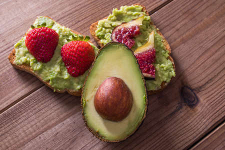 avocado toasts with fruits on rustic woodの写真素材