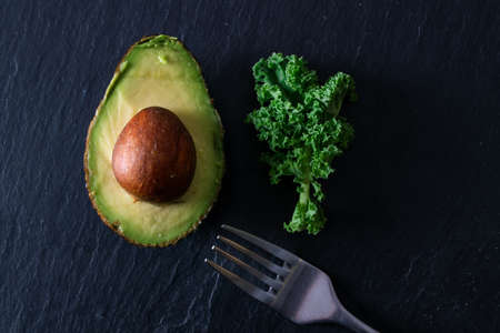 open avocado with vegetable leaf and forkの写真素材