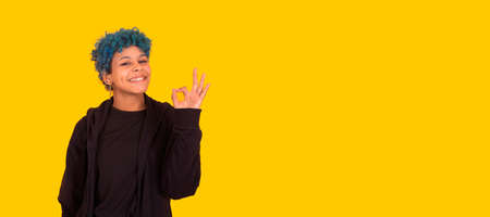 young african american girl or woman with blue hair isolated on yellow background