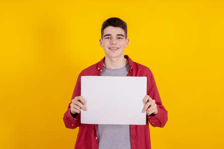 young teenager boy holding sign or signboard isolated on color backgroundの写真素材