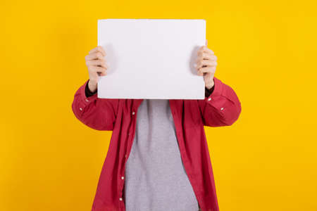 young teenager boy holding sign or signboard isolated on color backgroundの写真素材