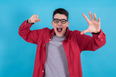 young man or teenage student isolated on color background with hand and raised fist screaming