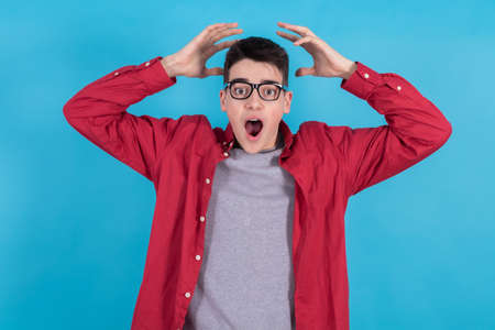 young man or teenage student isolated on color background with his hands on his head in amazementの写真素材