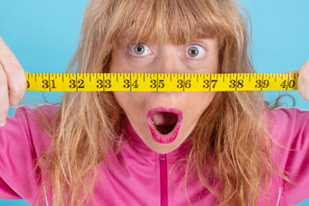 closeup of astonished woman looking at measuring tape, diet and slimmingの写真素材