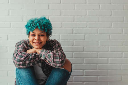 portrait of young afro american girl with blue hair at home or apartment smiling
