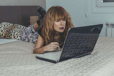 adult woman with laptop in the room or bedroomの写真素材