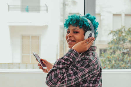 girl or woman with mobile phone and headphones at home