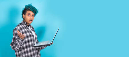 afro american girl with laptop computer isolated on blue backgroundの写真素材