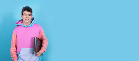 portrait of teenage student with laptop isolated on blue backgroundの写真素材