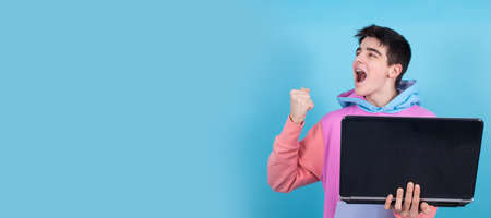 young teenage man or student with laptop isolated on background with surprise or success expression