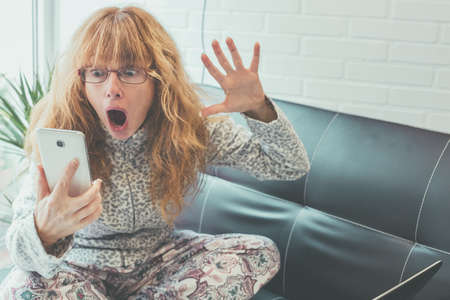 adult or senior woman with mobile phone and expression of amazement or problems